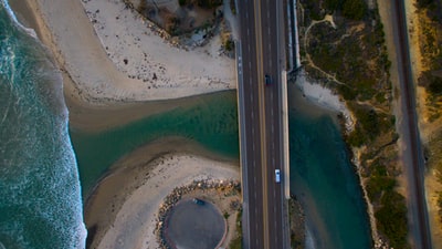 航空摄影的黑色和白色车辆道路与水体之间
